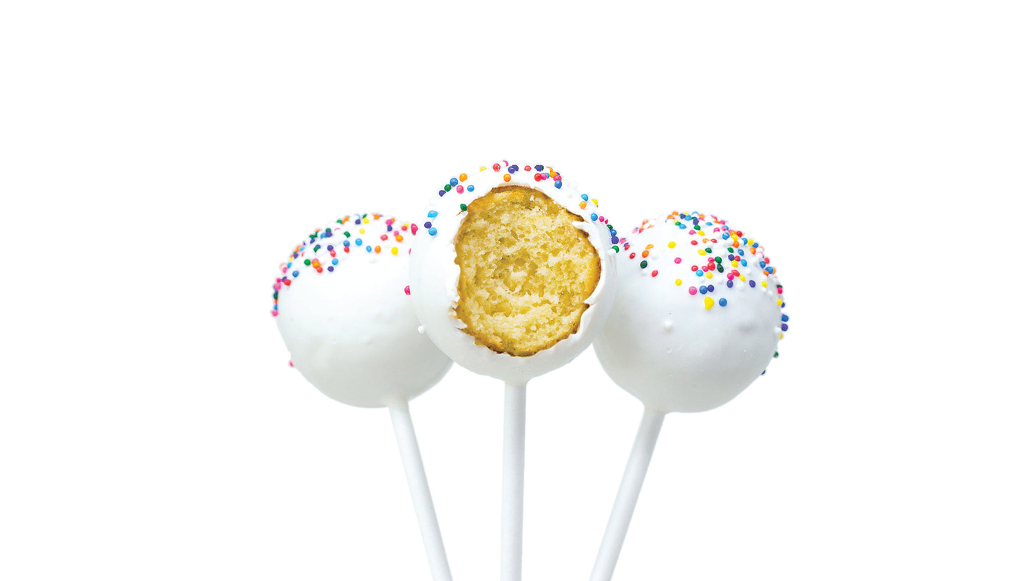 Three cake pops with white icing and colorful sprinkles on sticks, one of which has a bite taken out, showing the yellow cake inside, all set against a white background.